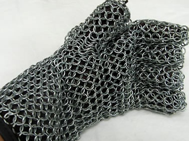 A hand is wearing a piece of stainless steel chainmail glove with black lining.